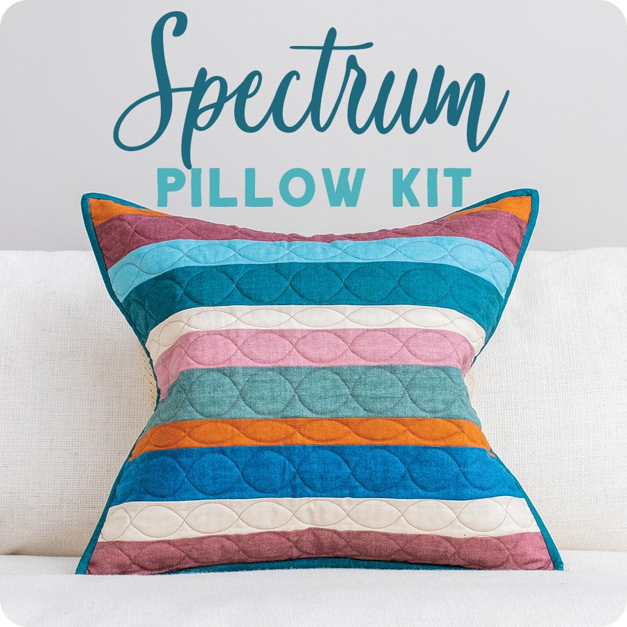 Edyta Sitar's Spectrum throw pillow sits on a couch and comes in a variety of colors