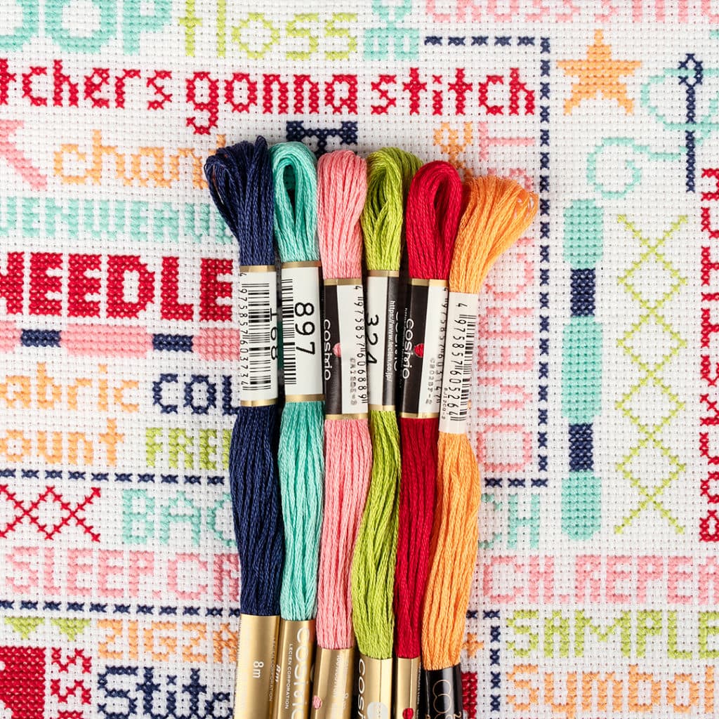 The Stitch-O-Graphy Cosmo floss pack has been arranged on top of the Stitch-O-Graphy cross stitch pattern, showcasing it's beautiful bold colors. 
