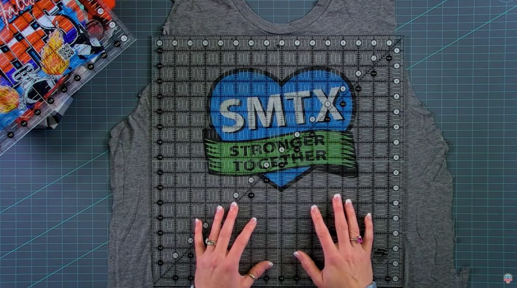 Image of a cut t-shirt with a quilting ruler over it to show how to cut for t-shirt quilts