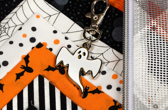 Ghost Enamel Keychain Charm sitting on a corner of the completed mystery design