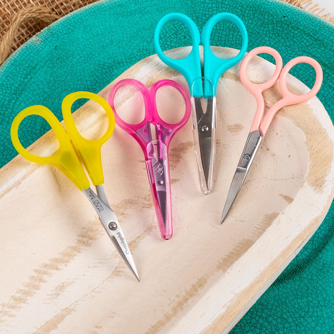 four pairs of different colored embroidery scissors used to help beginner cross stitchers trim threads