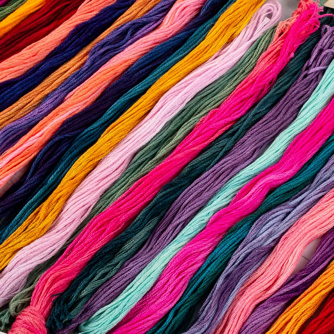 A rainbow of different colored threads and cross stitch floss
