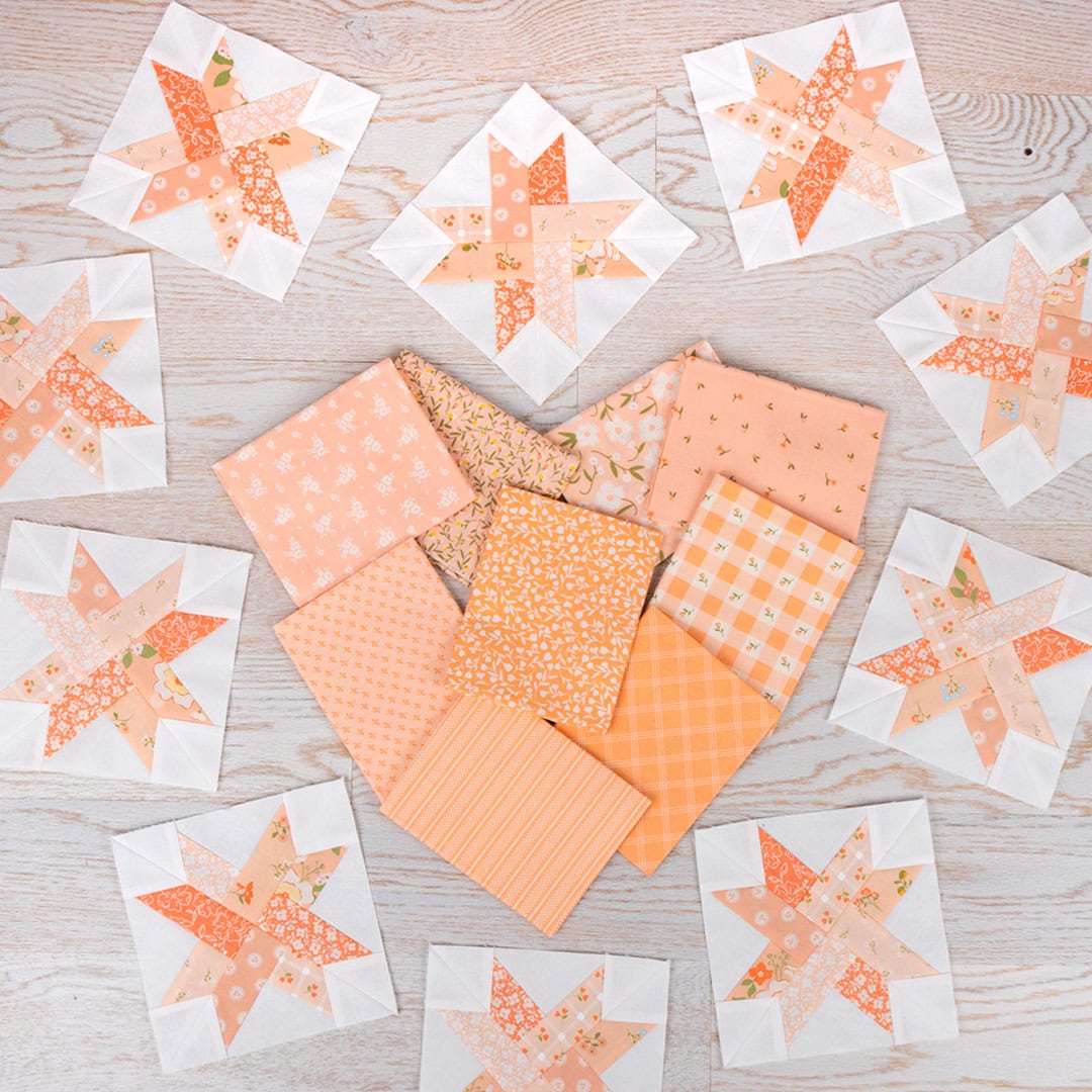 A heart made of folded fat quarters in the peach colors that are featured in the woven star blocks for the quilt. The heart is surrounded with 10 finished woven star blocks 