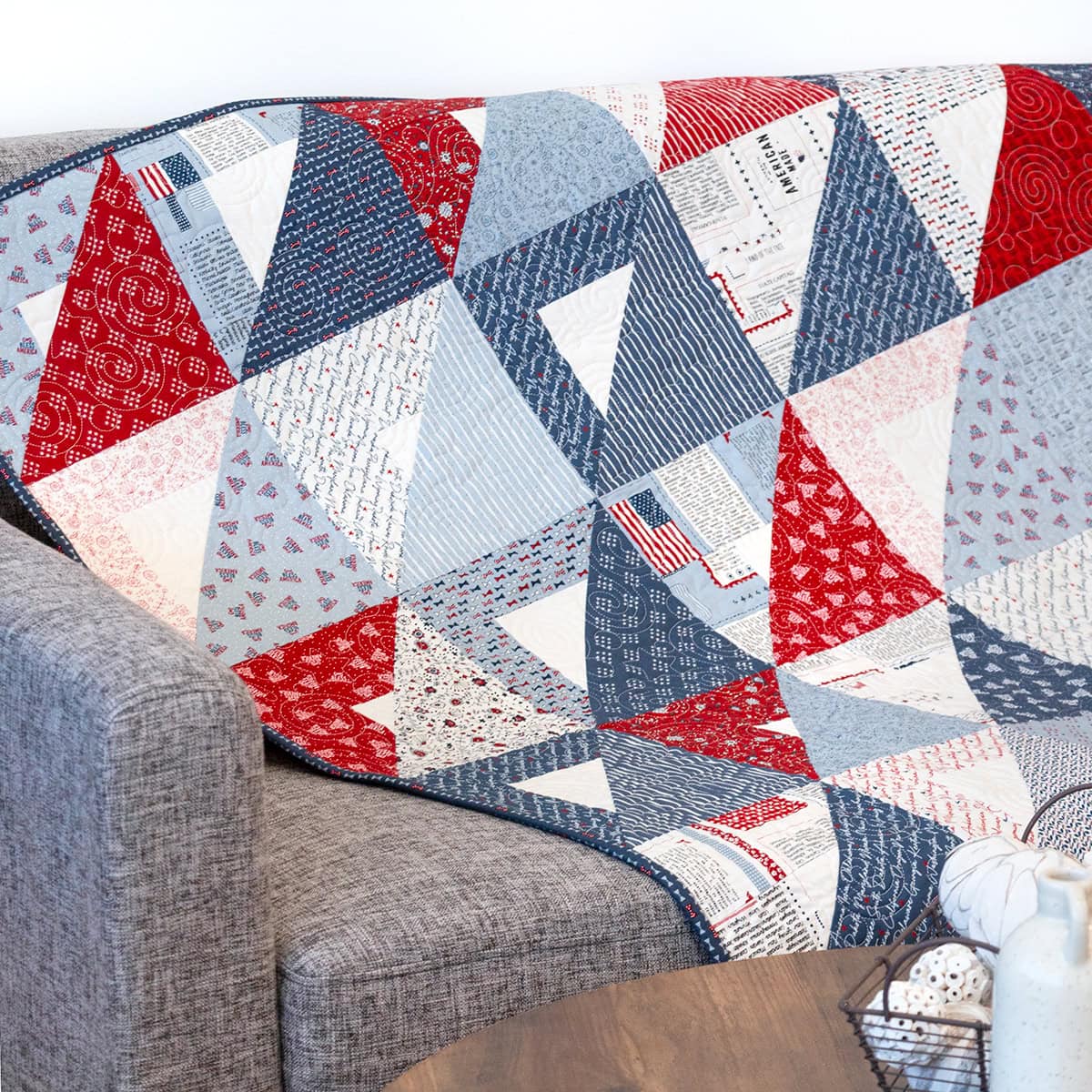Image of the Layer Cake Pocket Squares quilt displayed on a gray couch